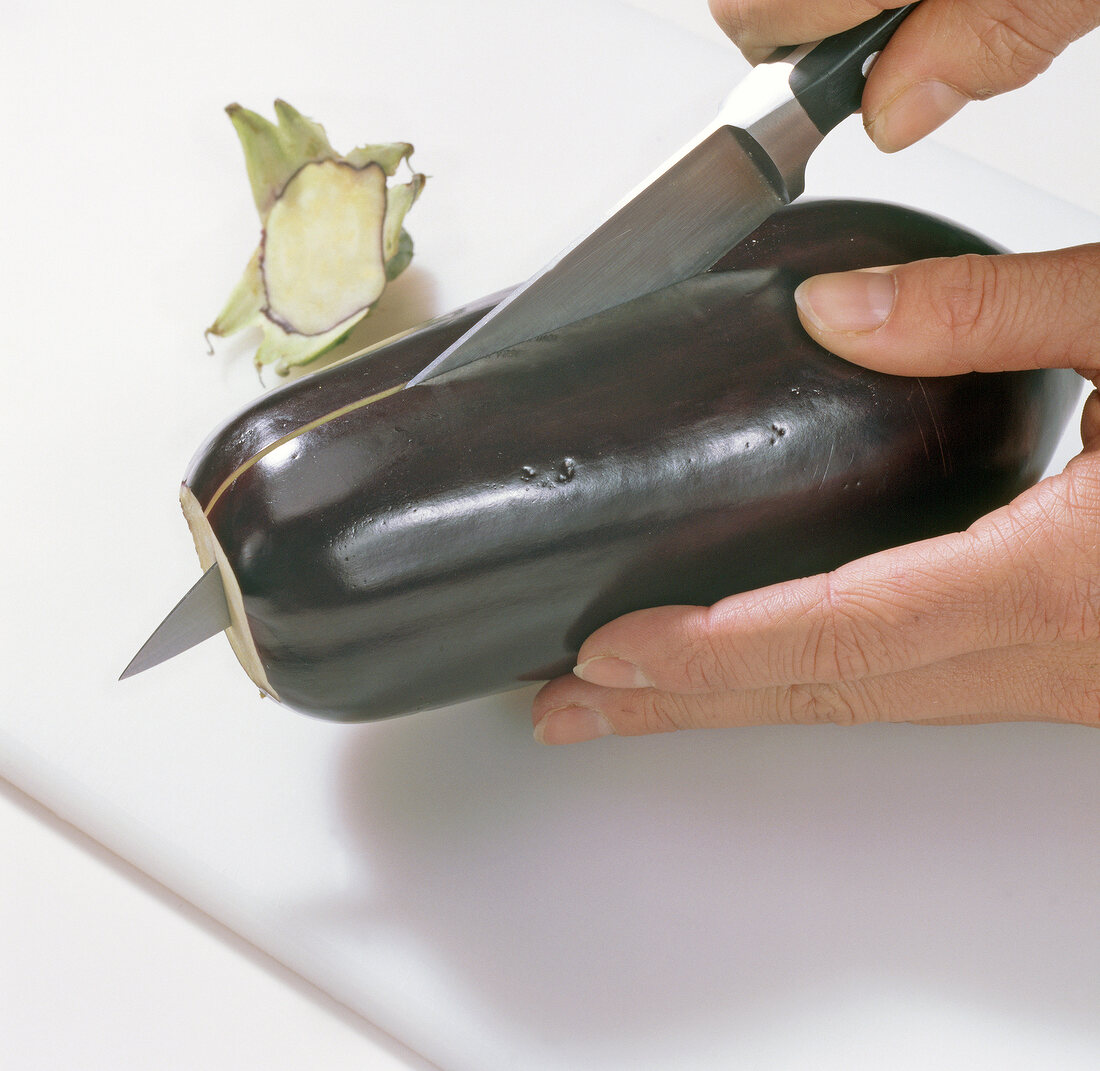 Close-up of hands cutting eggplant, step 2