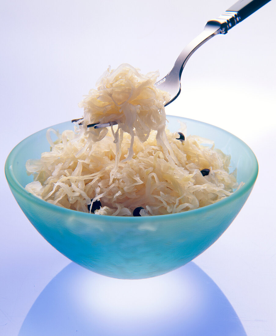 Bowl full of sauerkraut with fork on white background