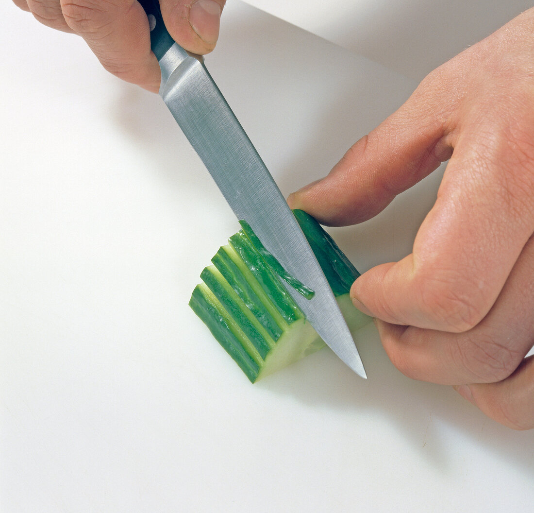 Close-up of cucumber being carved for decoration, step 1