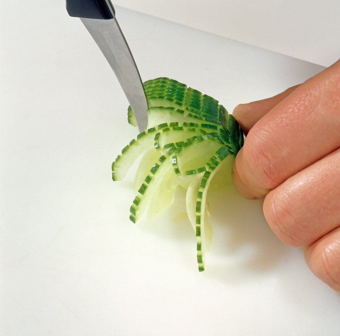 Close-up of cucumber being carved for decoration, step 3