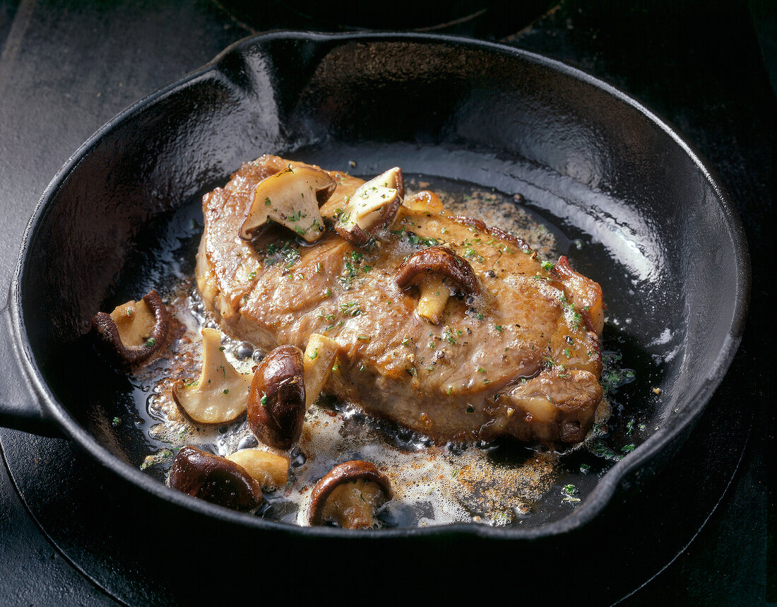 Close-up of beef sirloin steak with mushrooms in pan
