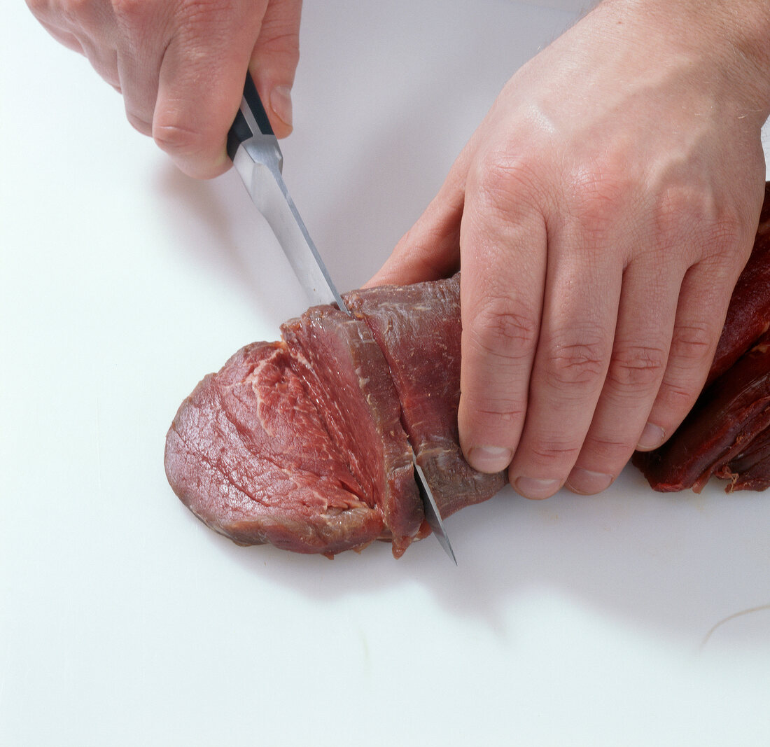 Close-up of hands cutting beef into pieces, step 1