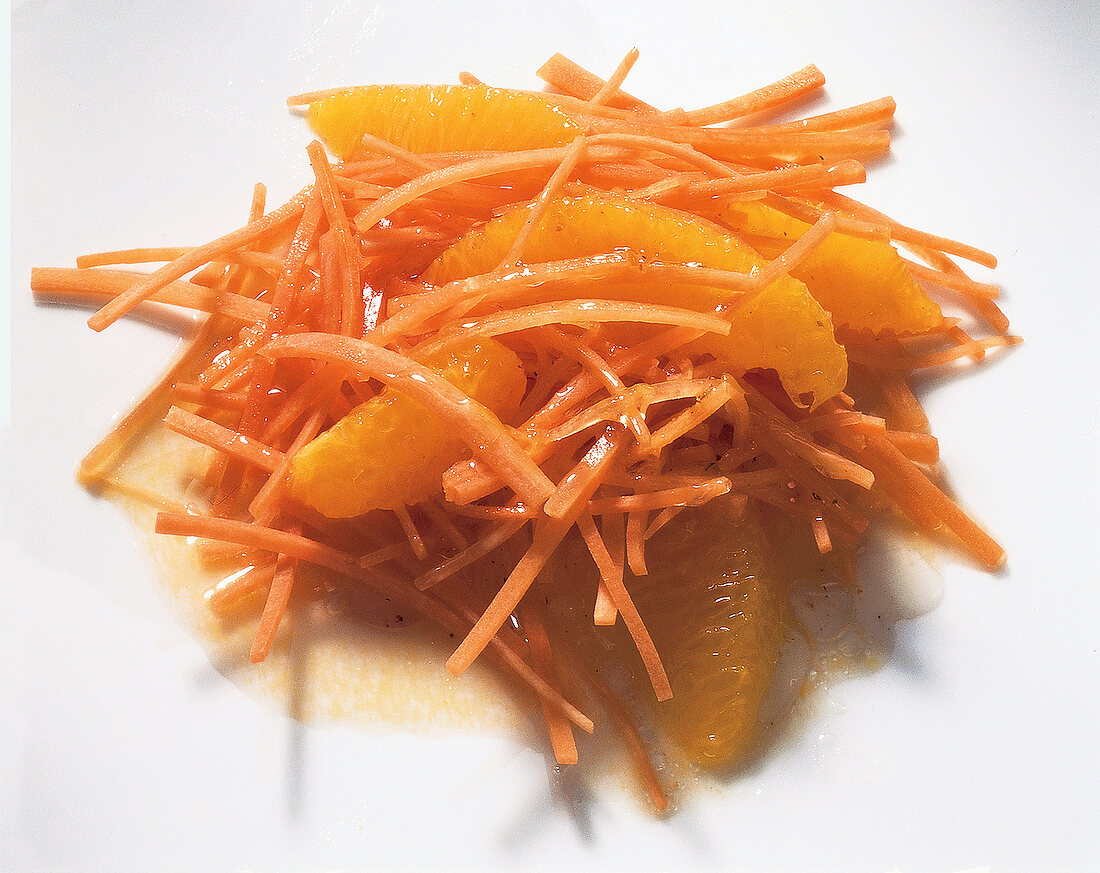 Close-up of carrot salad with orange dressing on white board