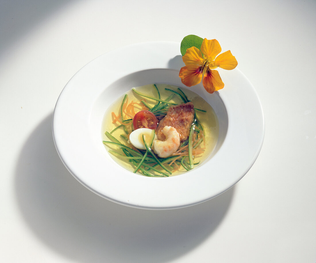 Bowl of fish, egg and sliced ??vegetables in aspic on white background