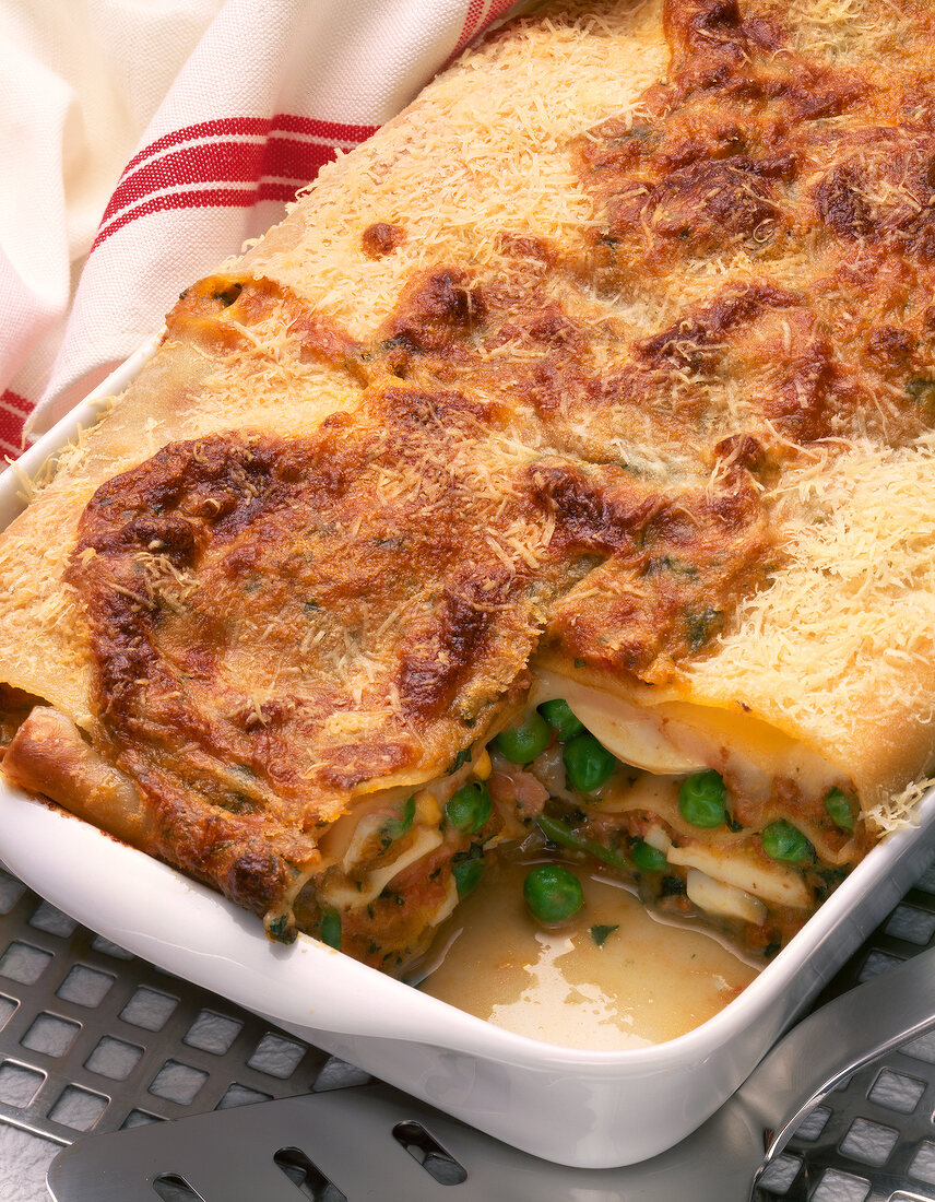 Close-up of lasagne al forno with mushrooms, ham and peas in tray