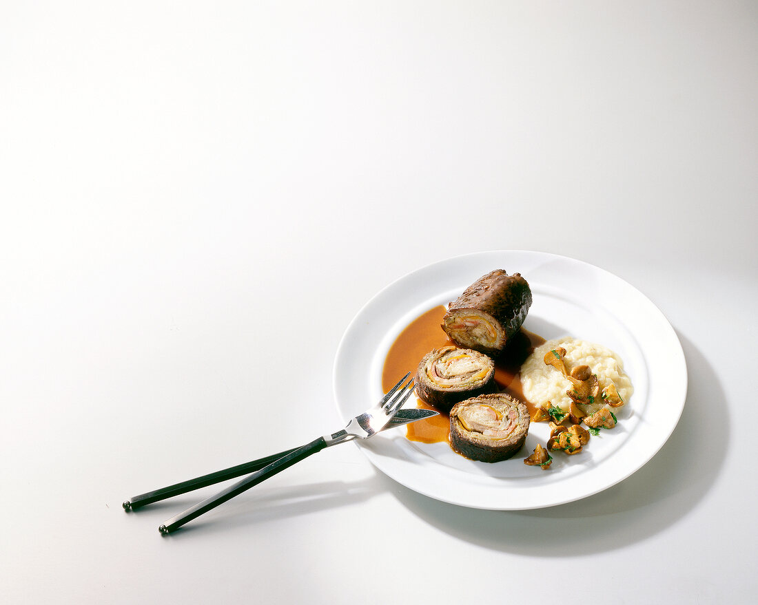 Beef roulade with artichoke filling on plate with fork and knife 