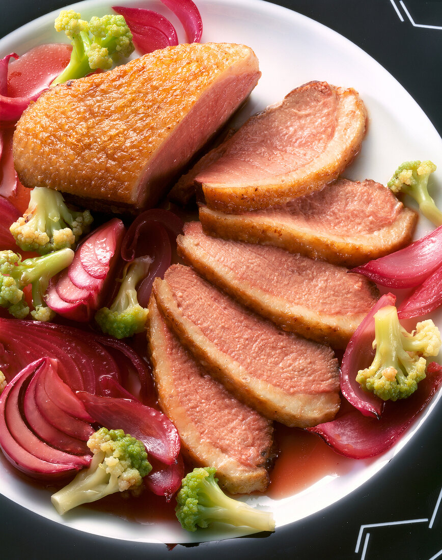 Marinated duck breast with cauliflower and red onions on plate