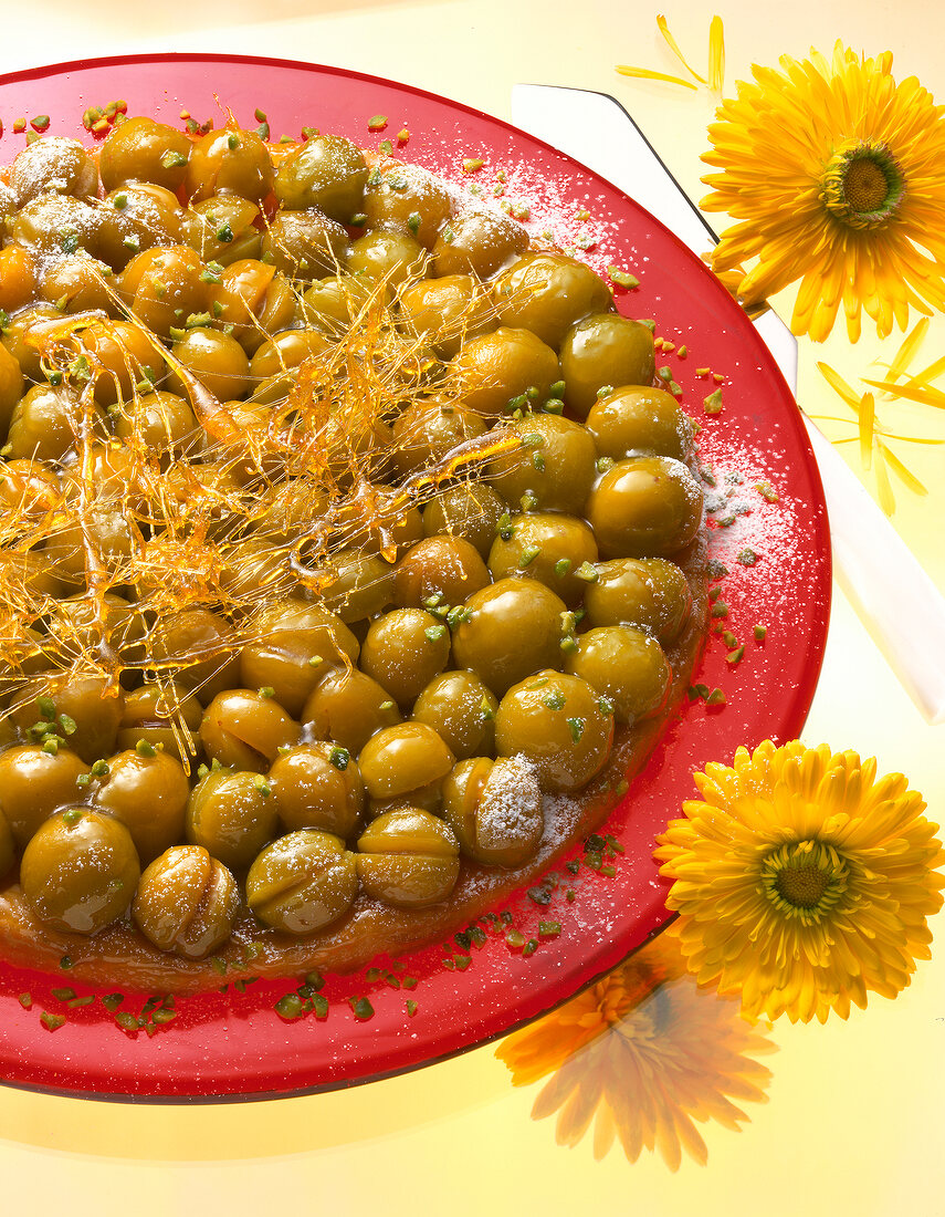 Close-up of mirabell cake on plate with yellow gerbera flowers on side