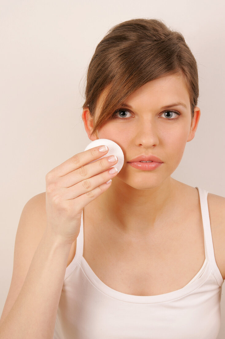 Portrait of gray eyed Magdalena woman with brown hair cleaning her face with pad