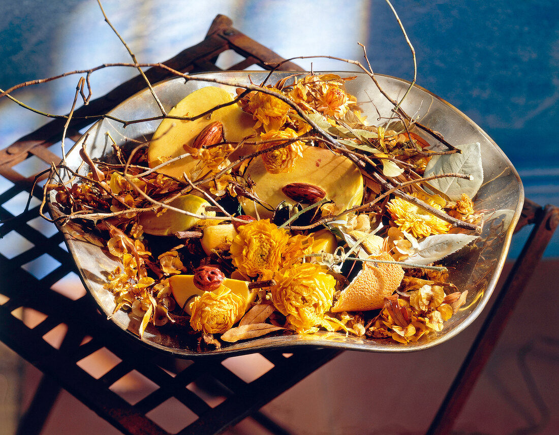 Schale mit getrockneten Blüten, Zweigen, Orangenschalen, gelb.