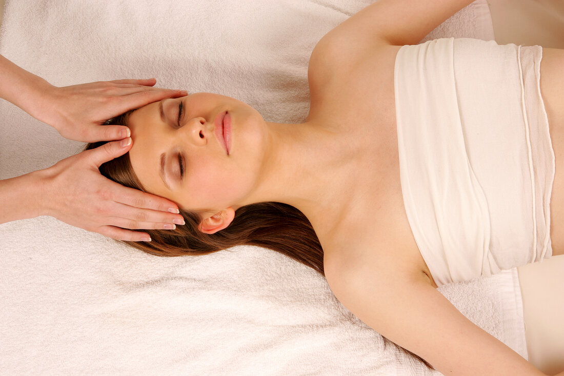 Magdalena woman lying on mat getting face massage, looking relaxed