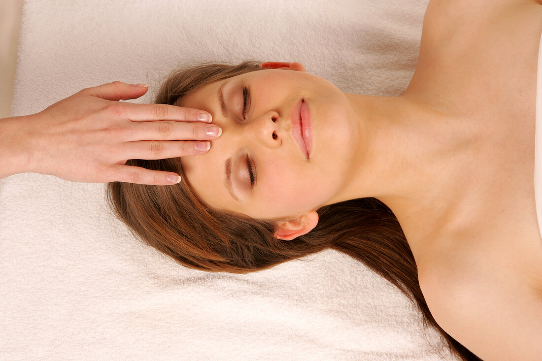 Magdalena woman lying on mat getting face massage, looking relaxed