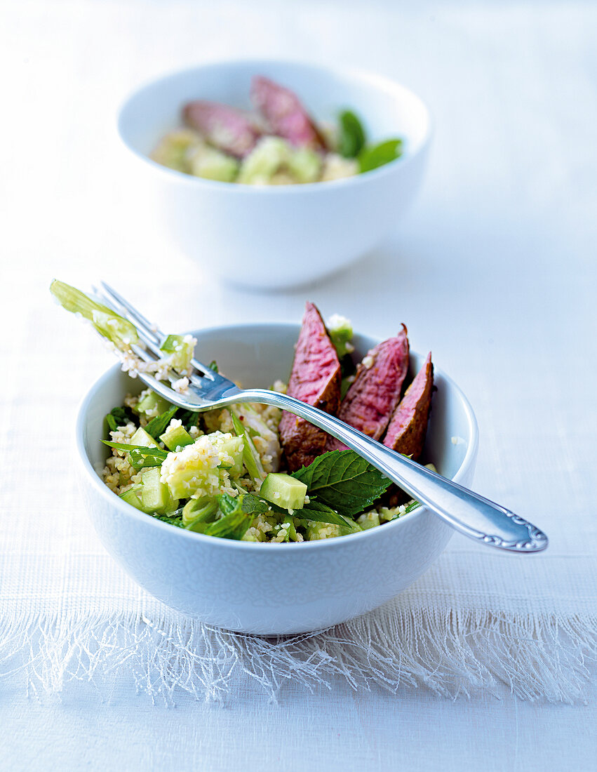 Bulgur and cucumber salad with lamb fillet in a bowl
