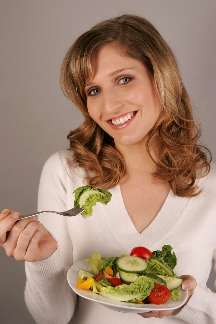 Charlotte Frau mit langen Haaren isst Blattsalat mit einer Gabel
