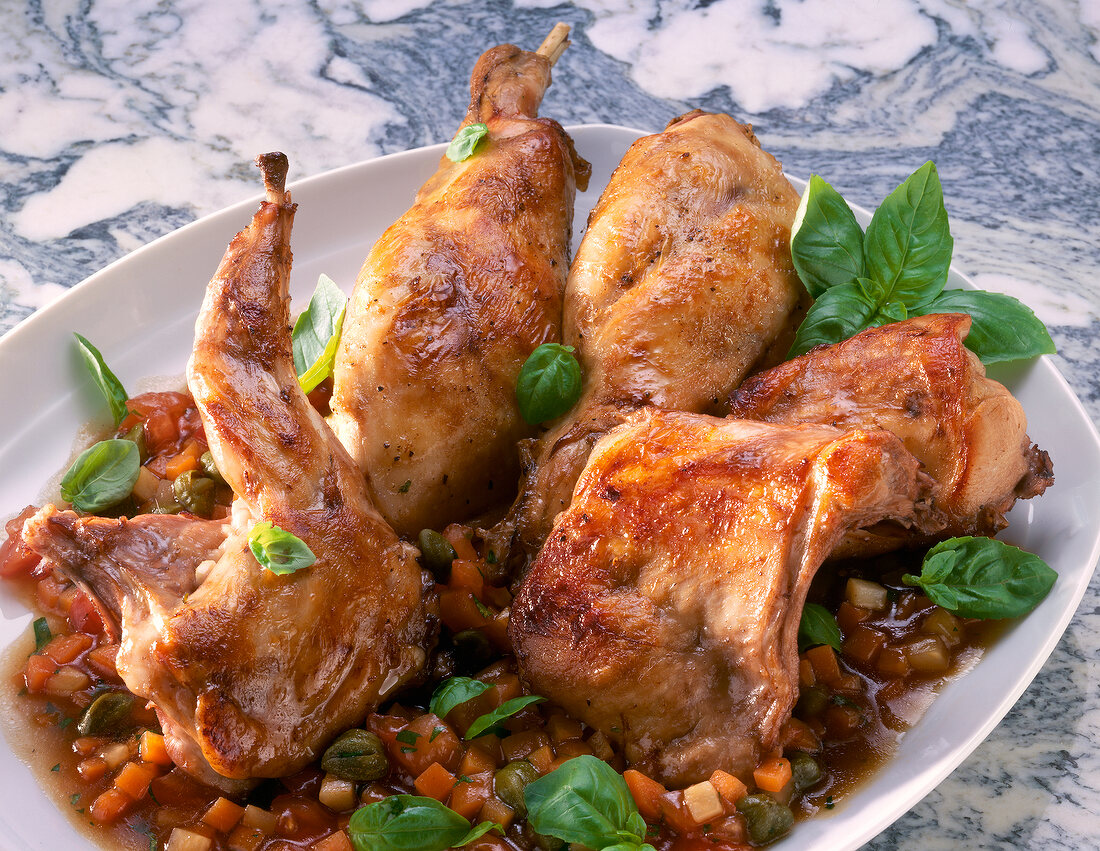 Braised rabbit's meat with tomatoes, capers and herbs on plate