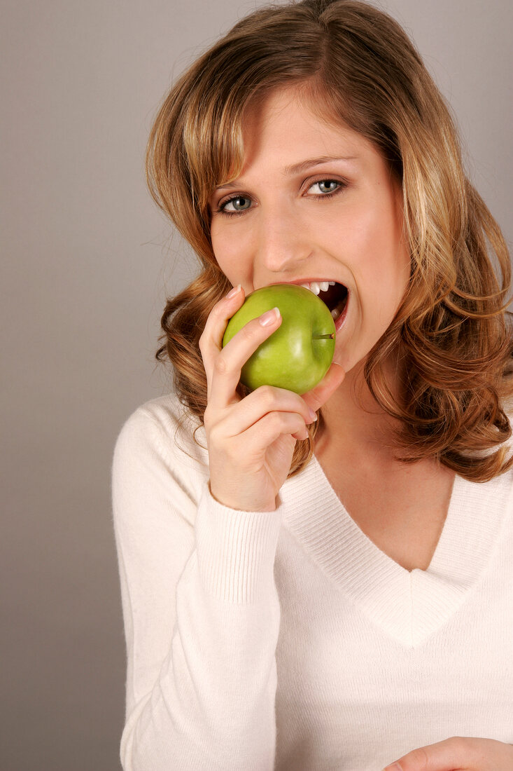 Frau mit langen Haaren beißt kräftig in Apfel, Detail