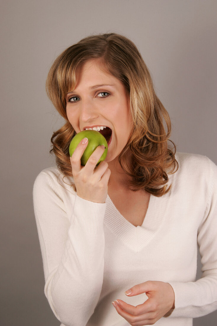 Portrait of young woman biting green apple
