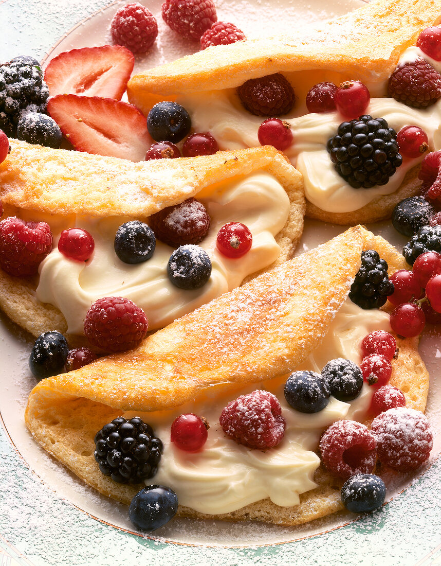 Close-up of foam omelettes with berries and icing sugar on plate