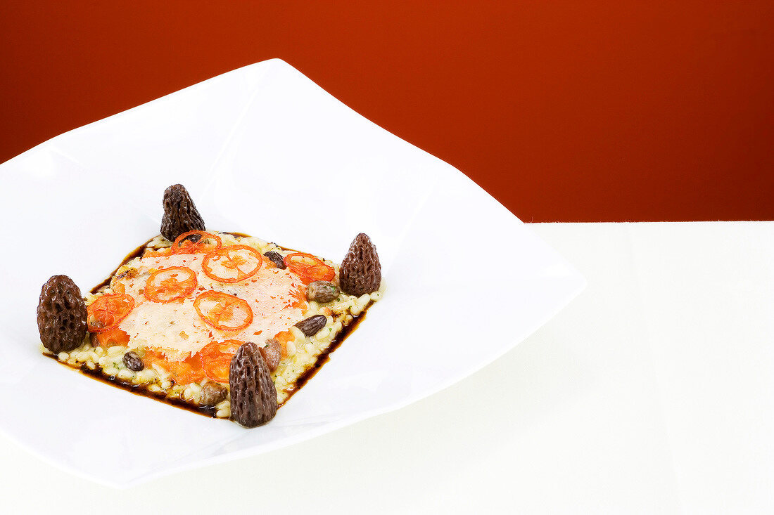 Wheat risotto with morel mushrooms and melted tomatoes on plate