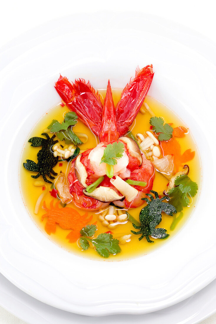 Steamed prawns in coriander broth on plate, overhead view