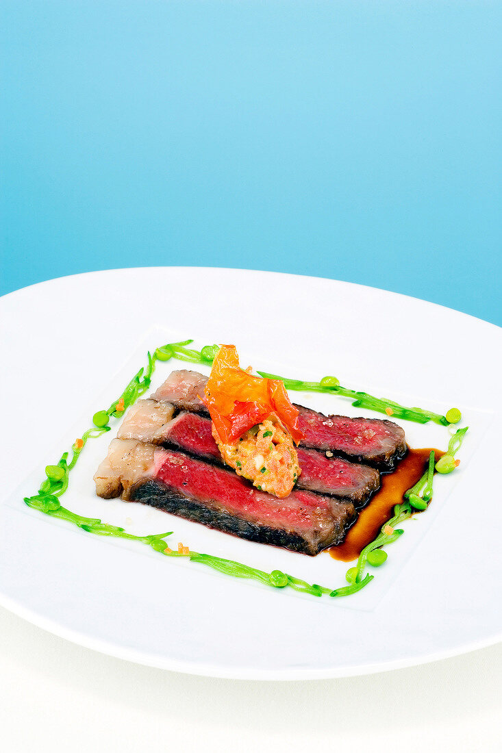 Beef prime rib, stewed tomatoes, olives and mustard seeds on plate