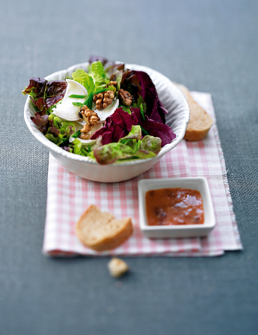 Goat cheese green salad with sauce and bread slices in bowl