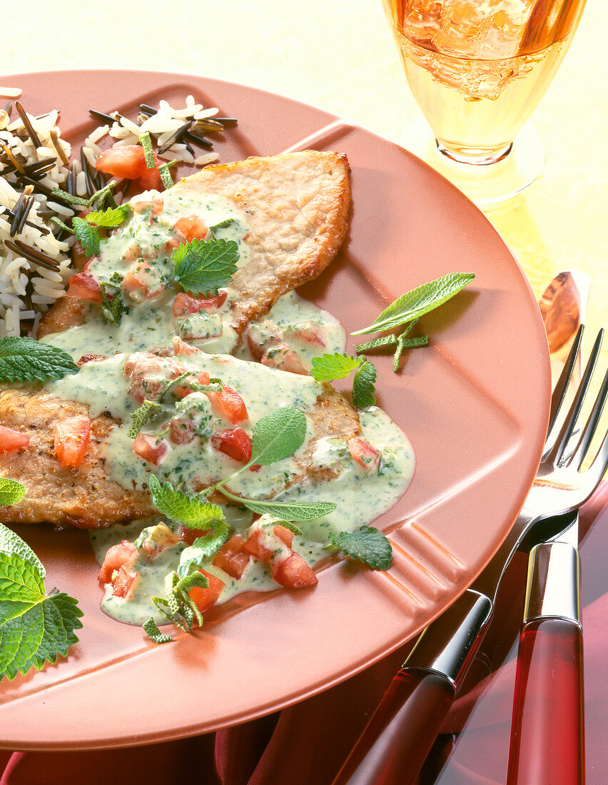 Schnitzel mit Zitronensauce, Tomaten und Salbei auf Teller