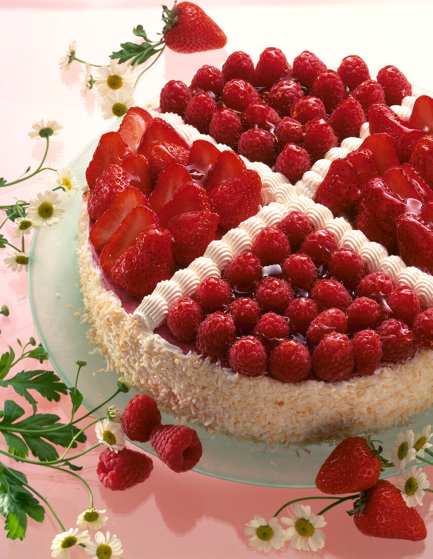 Pie with toasted coconut flakes, raspberry and strawberry on glass plate