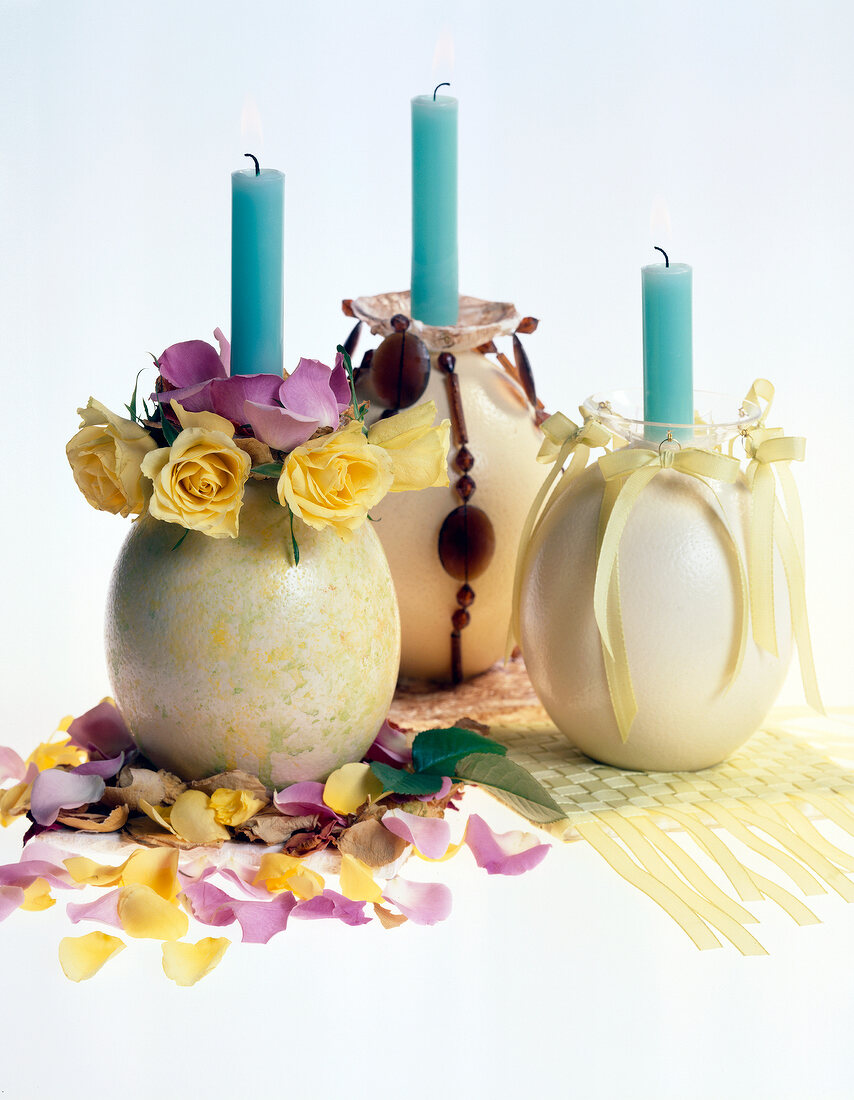 Egg shaped candlesticks with flowers, blue candles and scattered flower petals