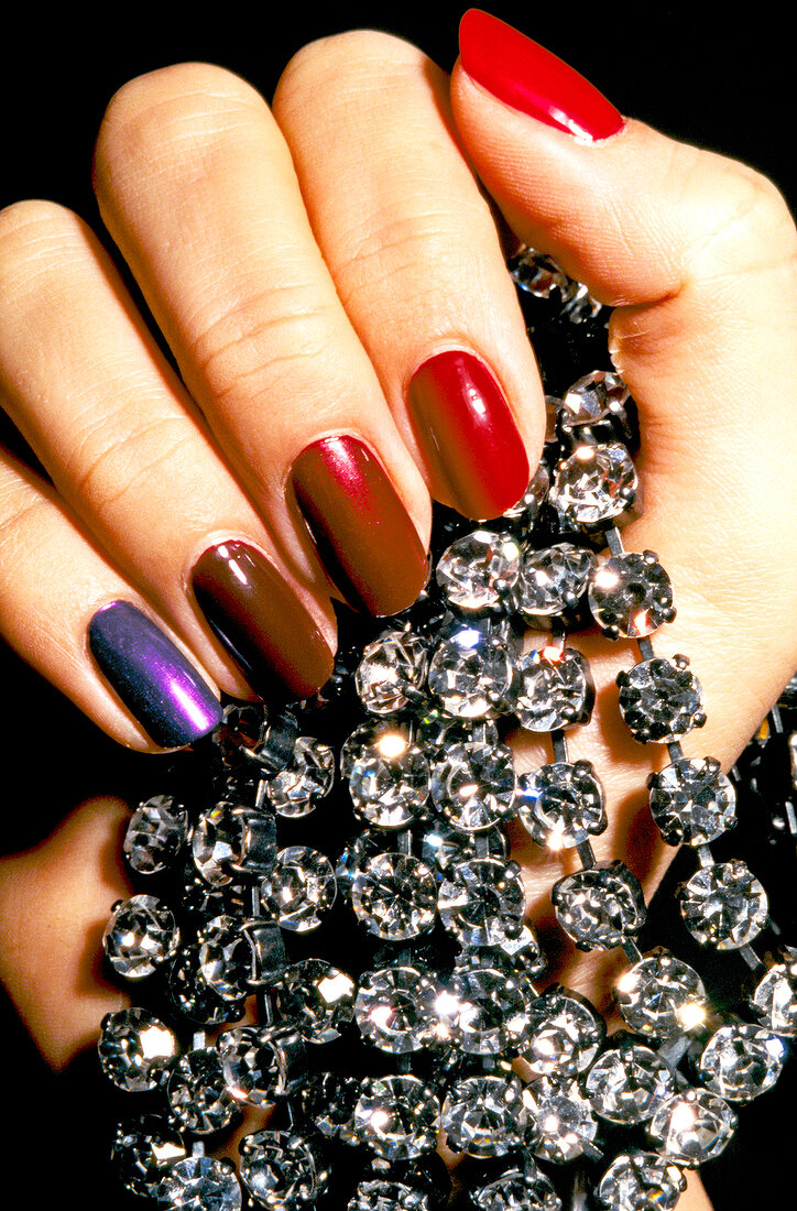 Close-up of woman wearing nail paint, holding diamond necklace