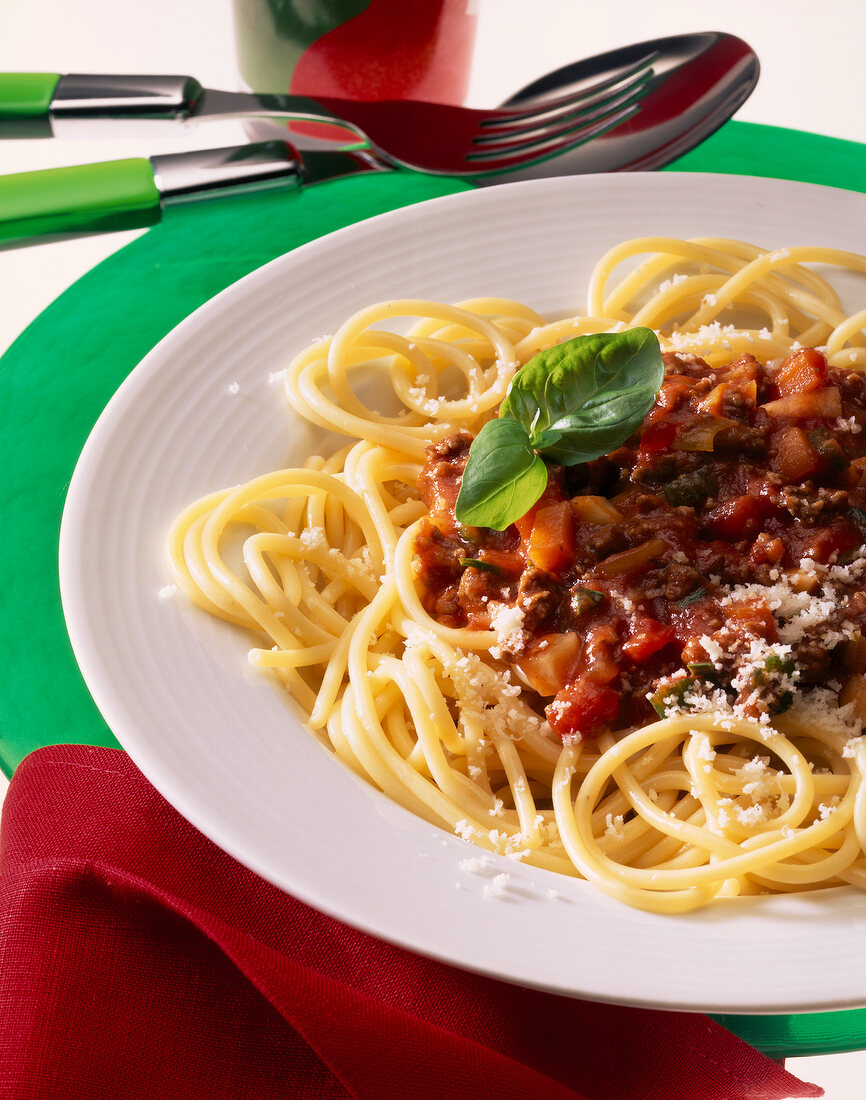 Spaghetti pasta with meat sauce, Parmesan cheese and basil leaves on plate