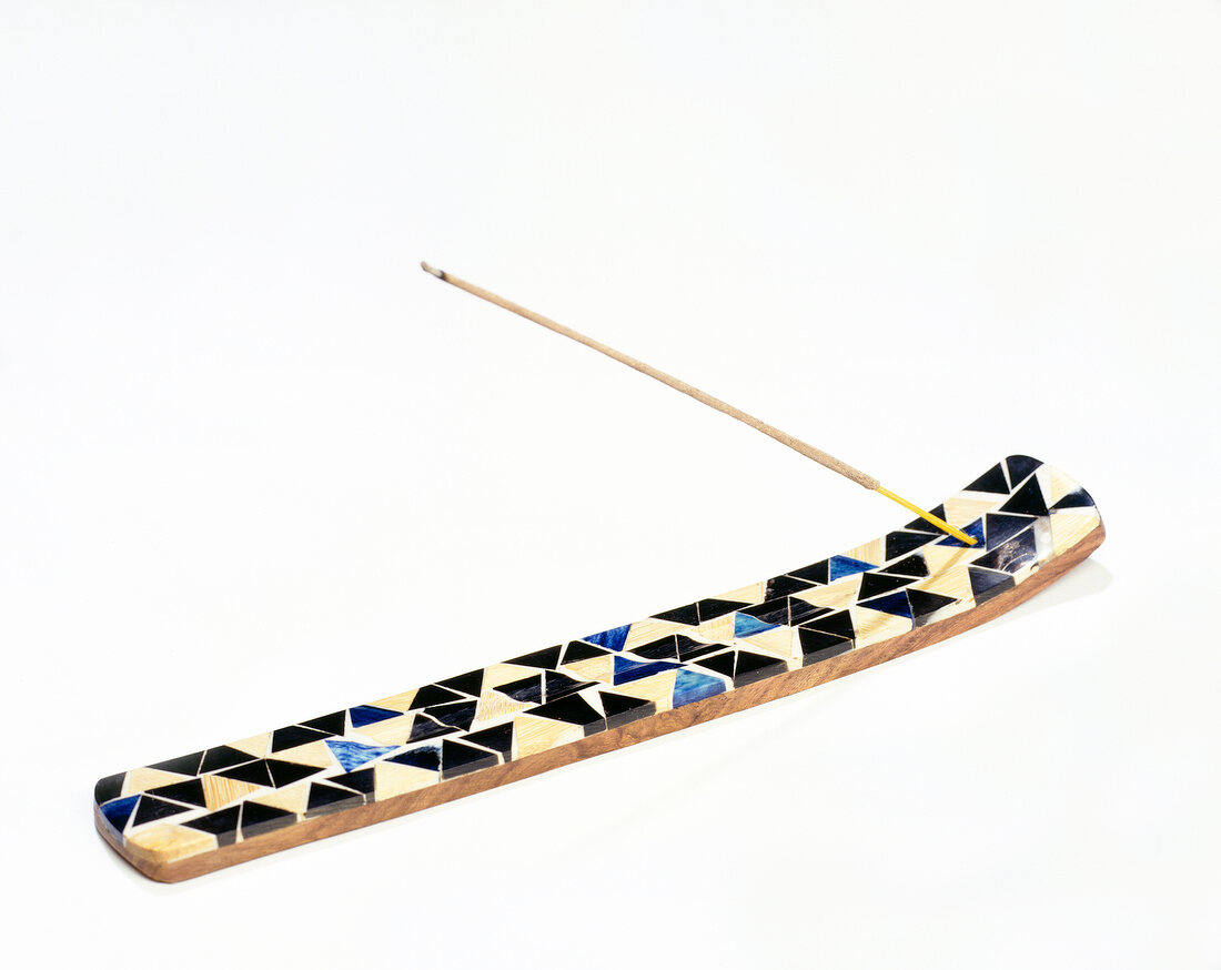 Close-up of long colourful incense holder on white background