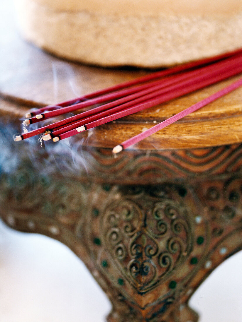 Nine incense sticks lying on table and smoke coming out of them, burning