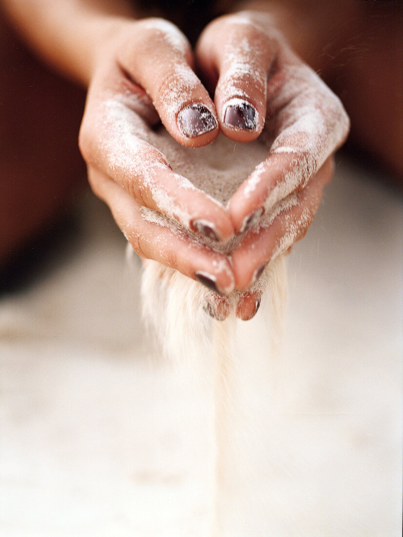 Close-up of sand slipping through woman's hands
