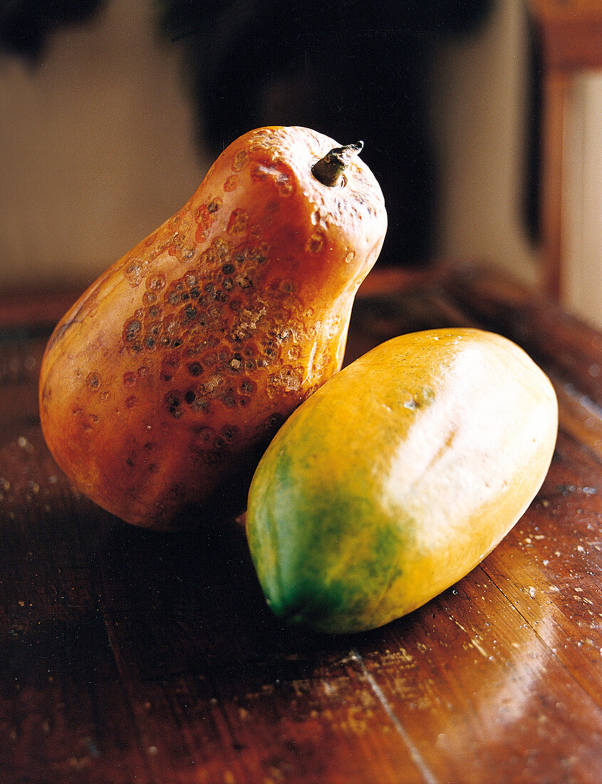 Two papayas lying on wooden table