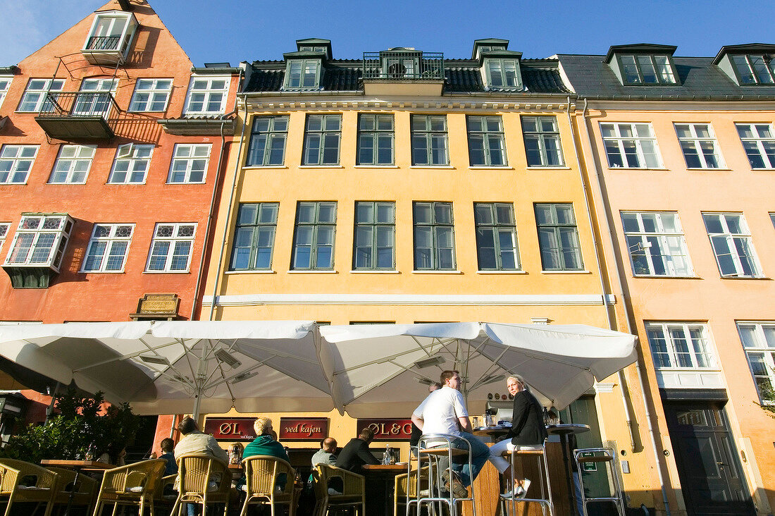 Bunte Häuser im Nyhavn in Kopenhagen , am Bürgersteig ein Café.