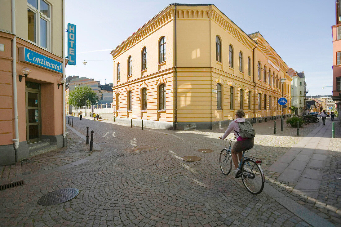 Cyclist riding bicycle in front of Hotel Continental, Malmo, Sweden