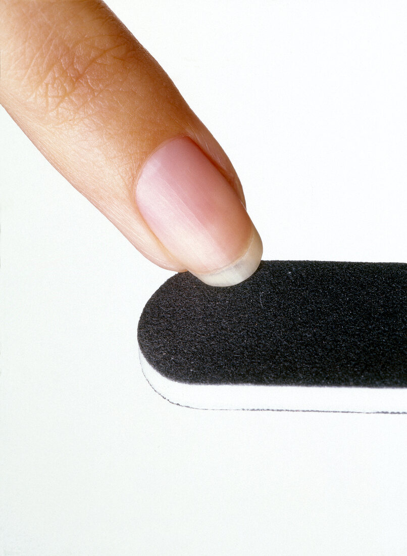 Close-up of woman scrubbing nail on nail scrub stone