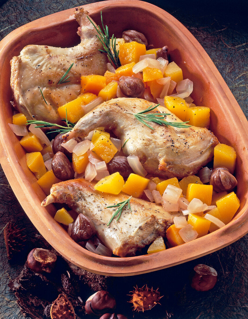 Close-up of rabbit leg with pumpkin and chestnuts in serving dish