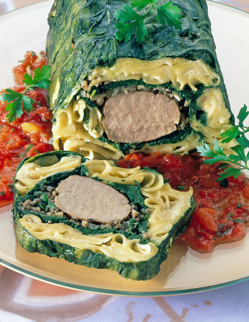 Close-up of pasta with sliced spinach terrine and tomato sauce on plate