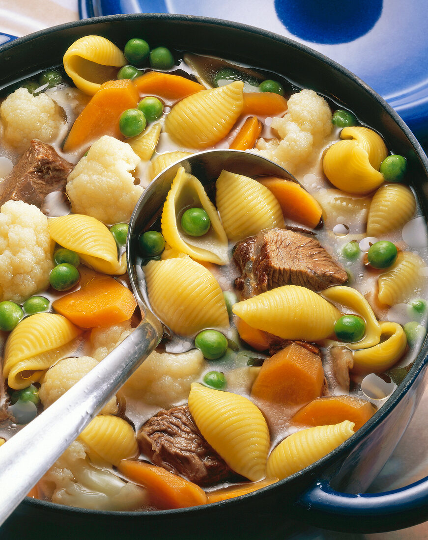 Close-up of noodle soup with beef shin, peas, carrots and Brussels sprouts in pot