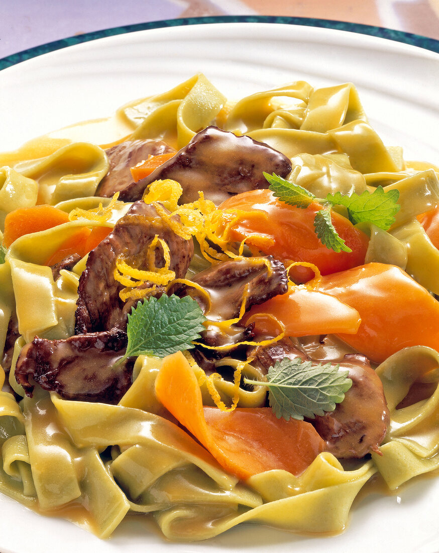 Close-up of spicy green noodles with carrots and beef on plate