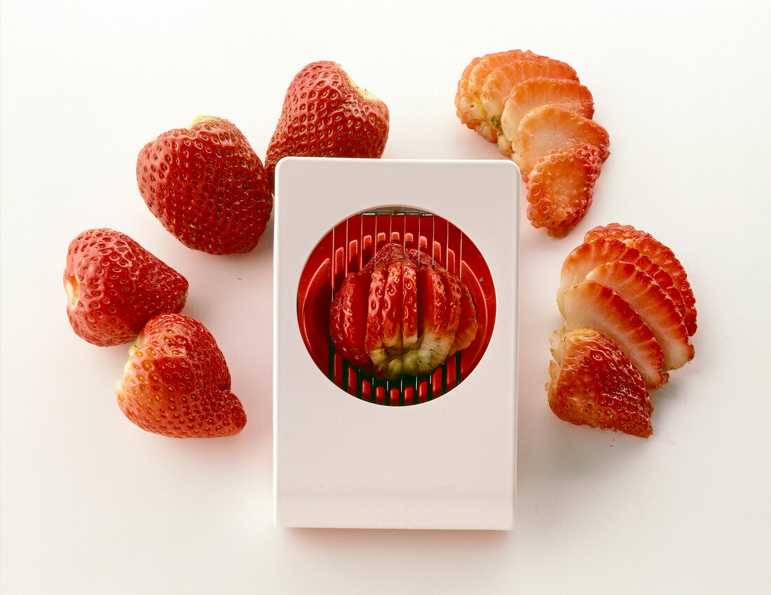 Strawberries sliced with egg slicer against white background