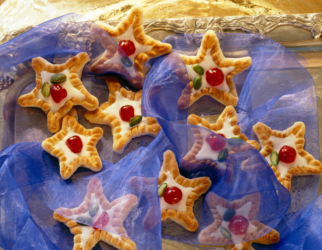 Close-up of konigsberg marzipan star biscuits with cherry and pistachios on top