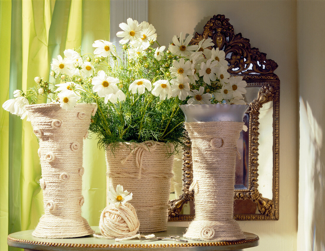 Three chamomile flower vases wrapped with sisal on table