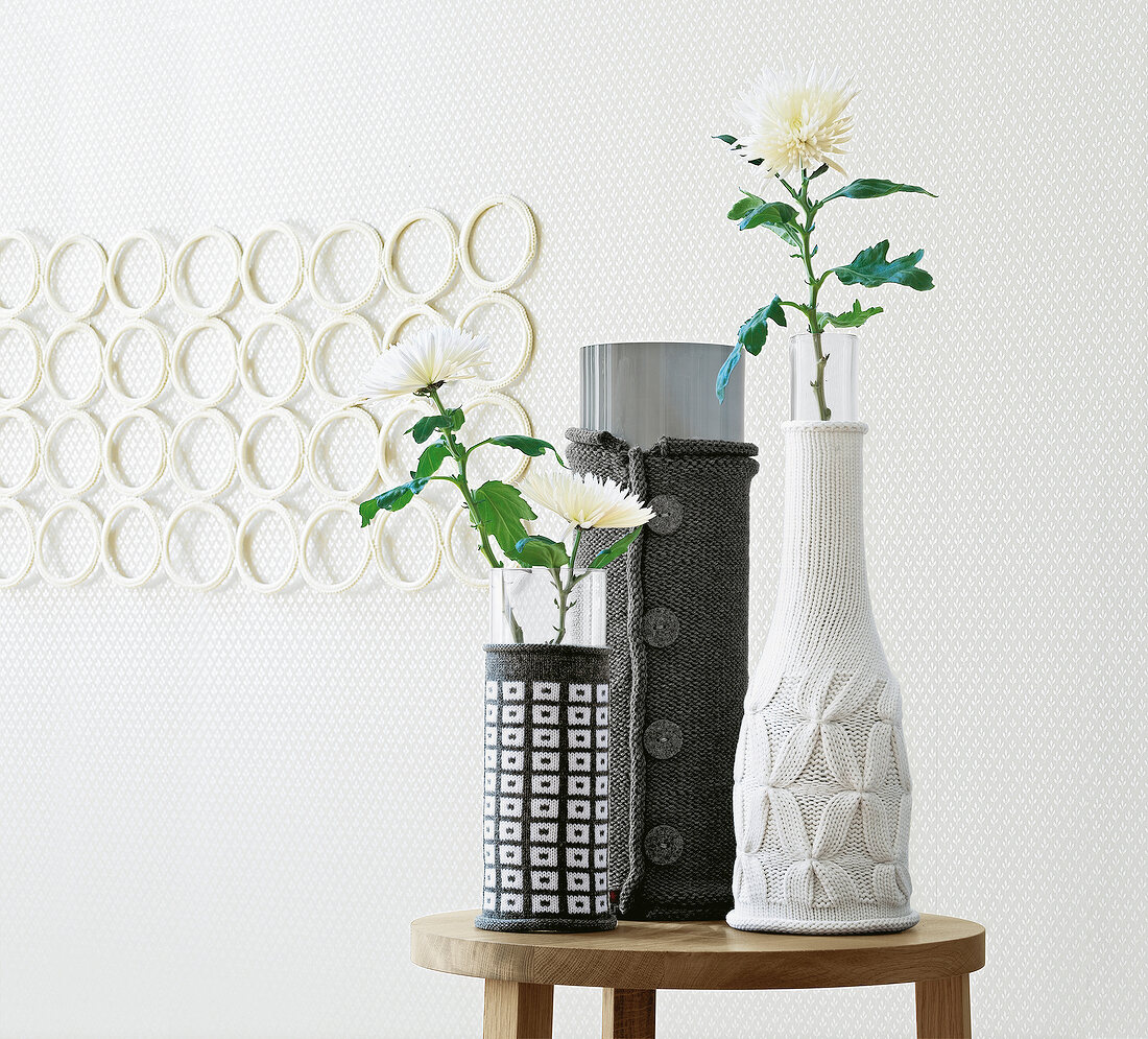 Chrysanthemen in Vasen mit Strickhussen in Grau und Weiß