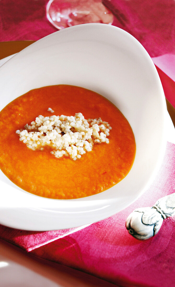 Tomato and carrot soup garnished with ginger and barley in bowl