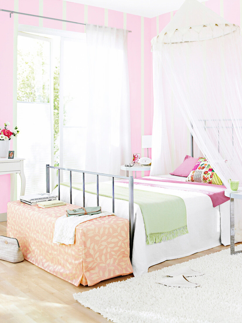 View of bedroom in white and pink with four poster bed