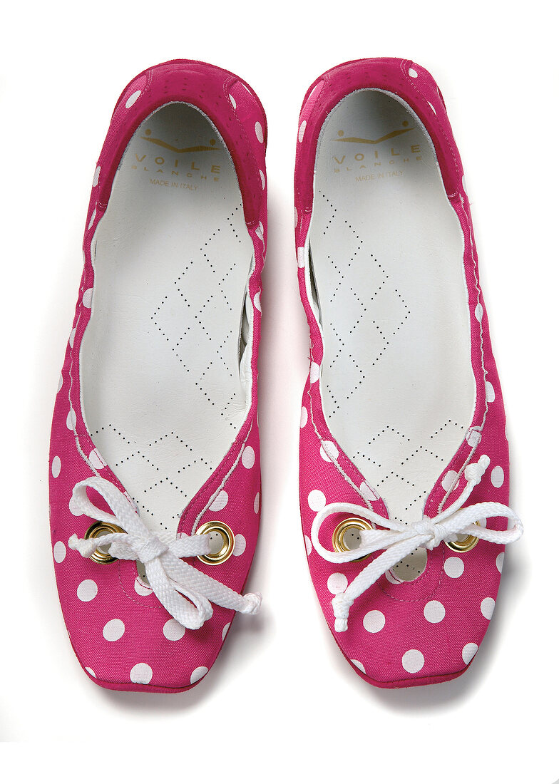 Close-up of pink ballerinas with white polka dots on white background