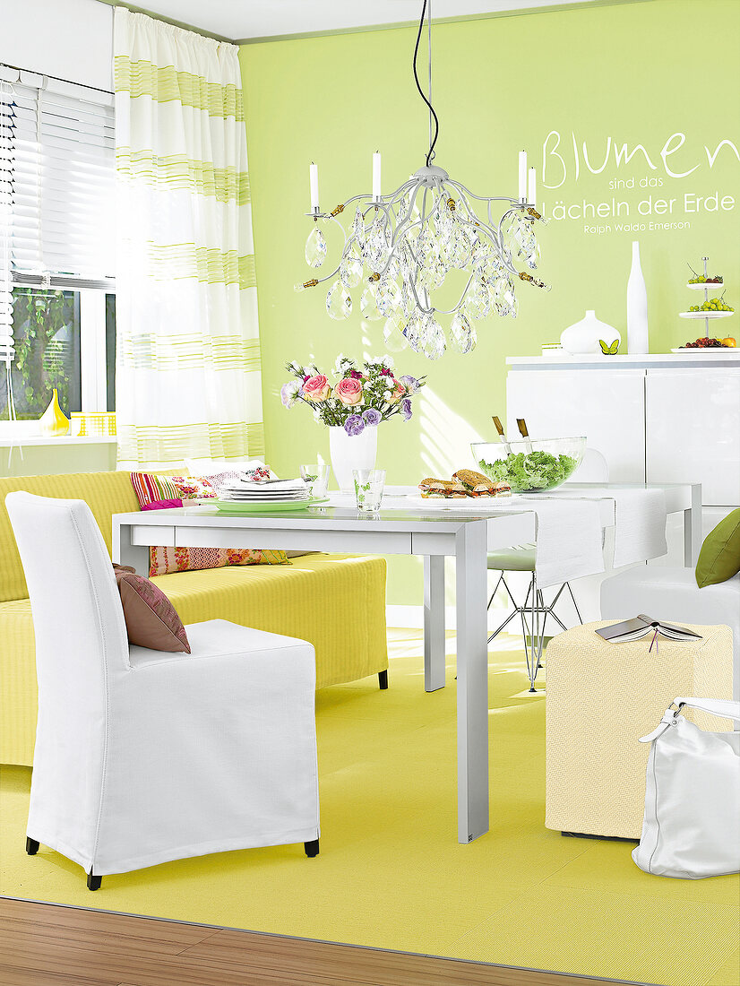 Dining area with chandelier, table, chair and yellow carpet against green wall